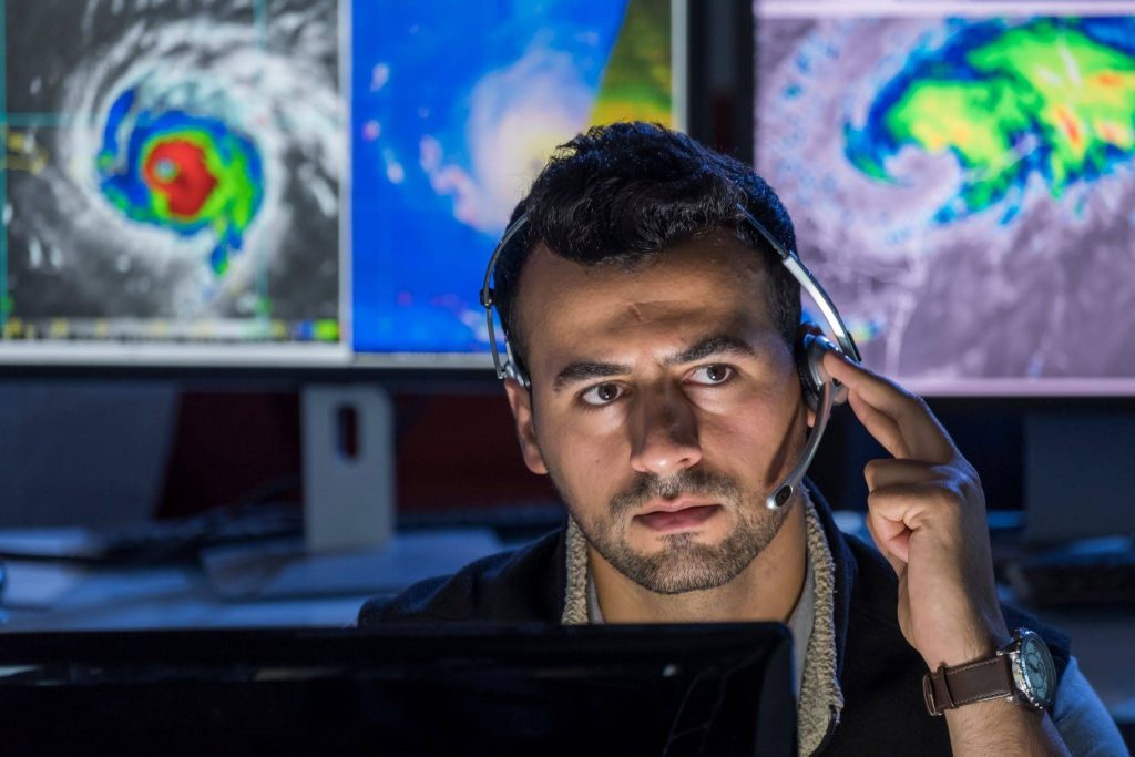man in office with headphones, monitoring weather events